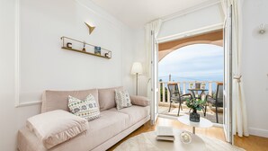 A modern living room with a beige sofa, a round coffee table, and a view of an outdoor balcony.