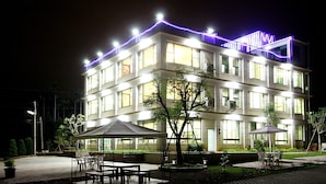 A multi-story building with a flat roof, large windows, and outdoor seating areas with tables and chairs. - Jing Guan Yuan (Zhushan)