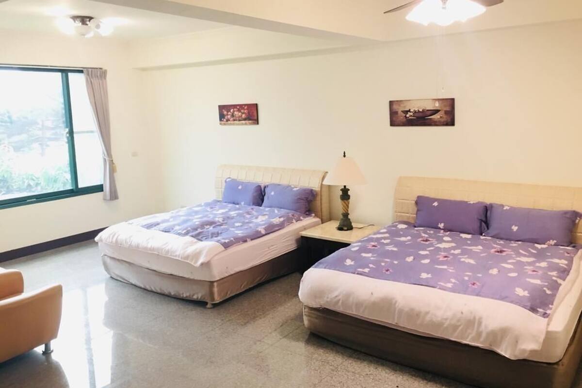 A hotel room with two beds, a ceiling fan, and a window with curtains.