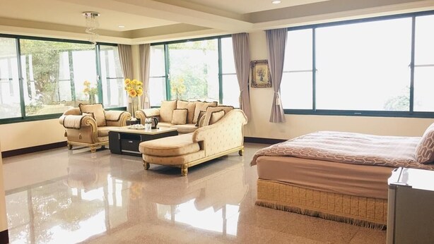 A spacious hotel room with a large bed, a sofa, and a coffee table. There are large windows providing natural light and a view of the outdoors. - Jing Guan Yuan (Zhushan)
