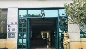 A building entrance with a large glass door, a welcome sign, and a bear statue. - Jing Guan Yuan (Zhushan)