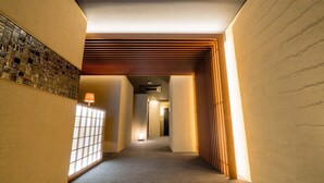 A hallway with a wooden slatted ceiling, a tiled wall, and a carpeted floor. - RESI STAY ANDON  (Kyoto)