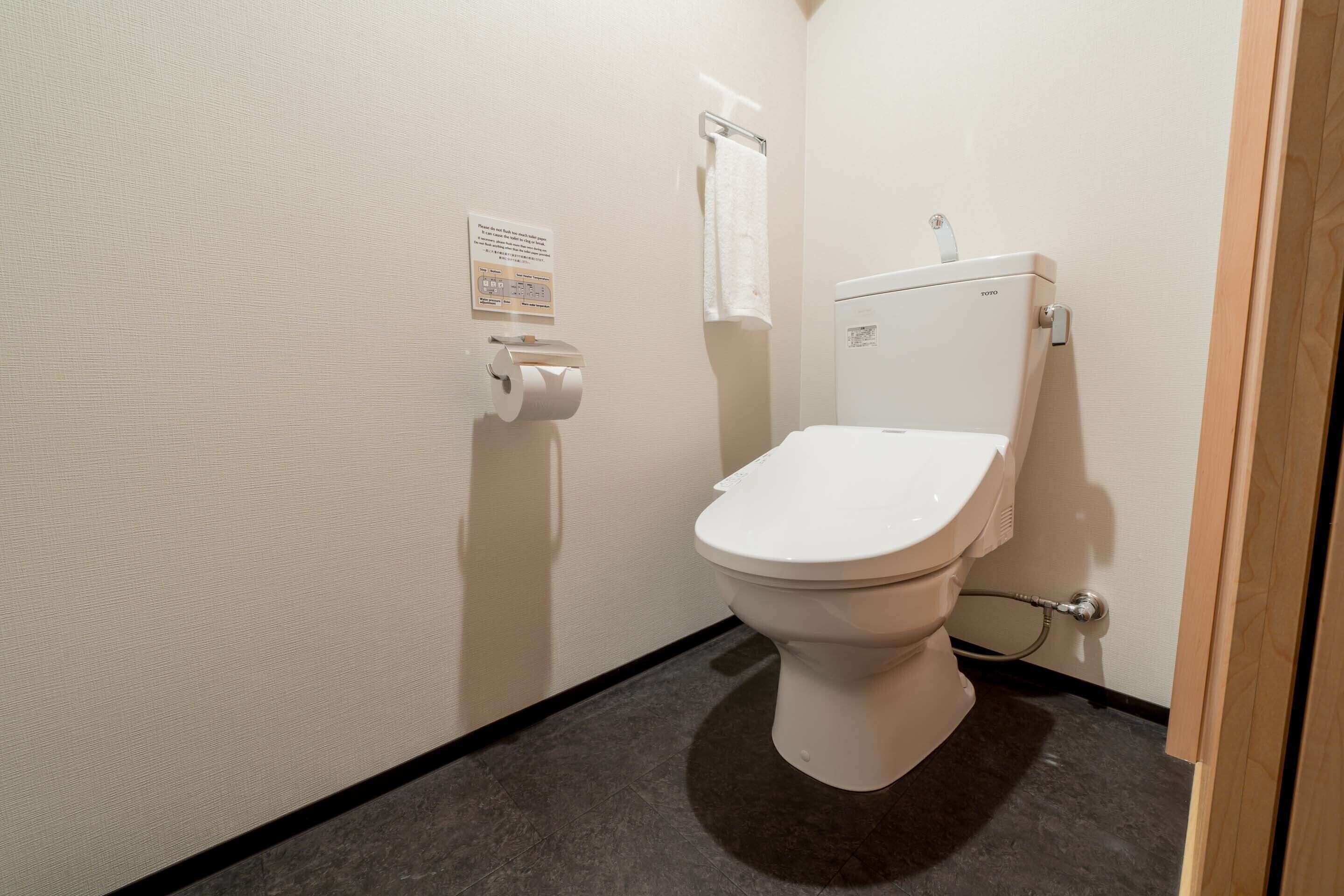 A small, clean bathroom with a toilet, a paper towel dispenser, and a hand dryer.