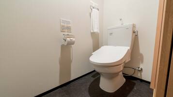 A small, clean bathroom with a toilet, a paper towel dispenser, and a hand dryer.