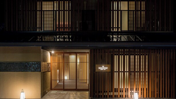 A hotel entrance with a wooden facade, a sign reading "RESIDENCE STAY," and two lanterns on the ground. - RESI STAY ANDON  (Kyoto)