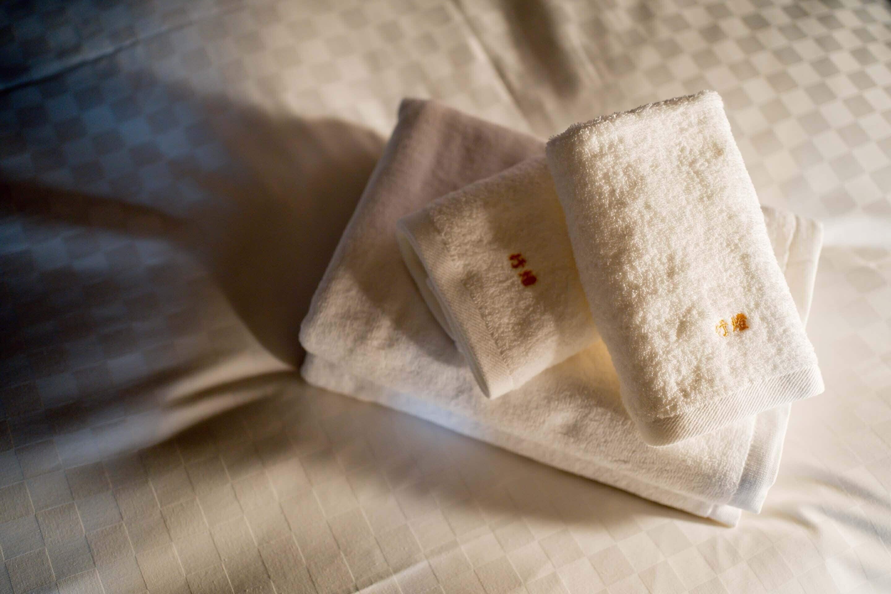 Neatly folded towels on a bed with a checkered pattern.