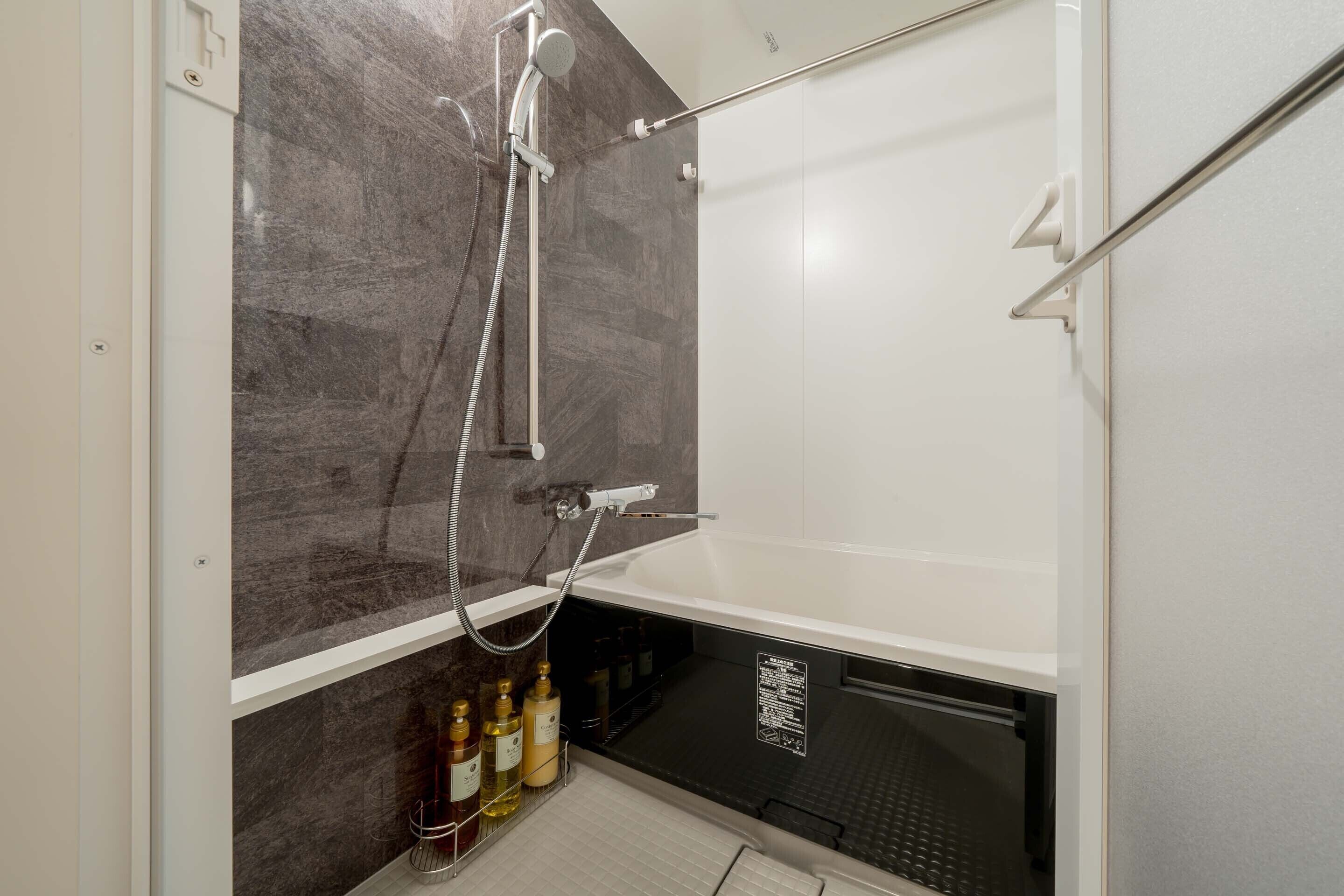 A modern bathroom with a glass-enclosed shower, a white bathtub, and a shelf with toiletries.