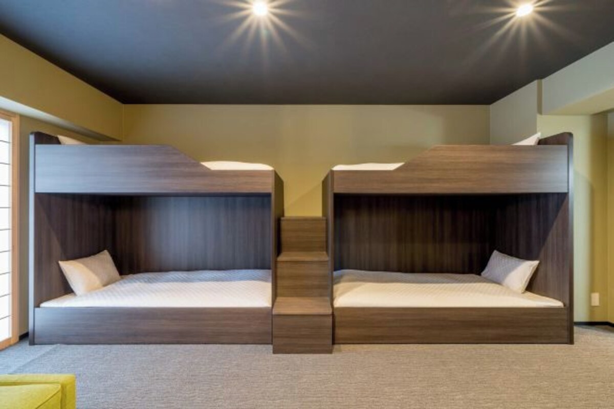 A room with two bunk beds, a staircase, and a yellow chair.