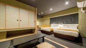 A hotel room with a large sliding door, two beds with yellow bedding, a desk, and a small table with patterned cushions. - RESI STAY ANDON  (Kyoto)