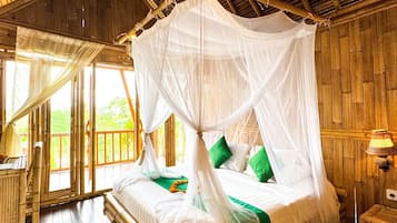Un lit à baldaquin en bois, avec un ciel de lit blanc, des oreillers verts et un plancher en bois.