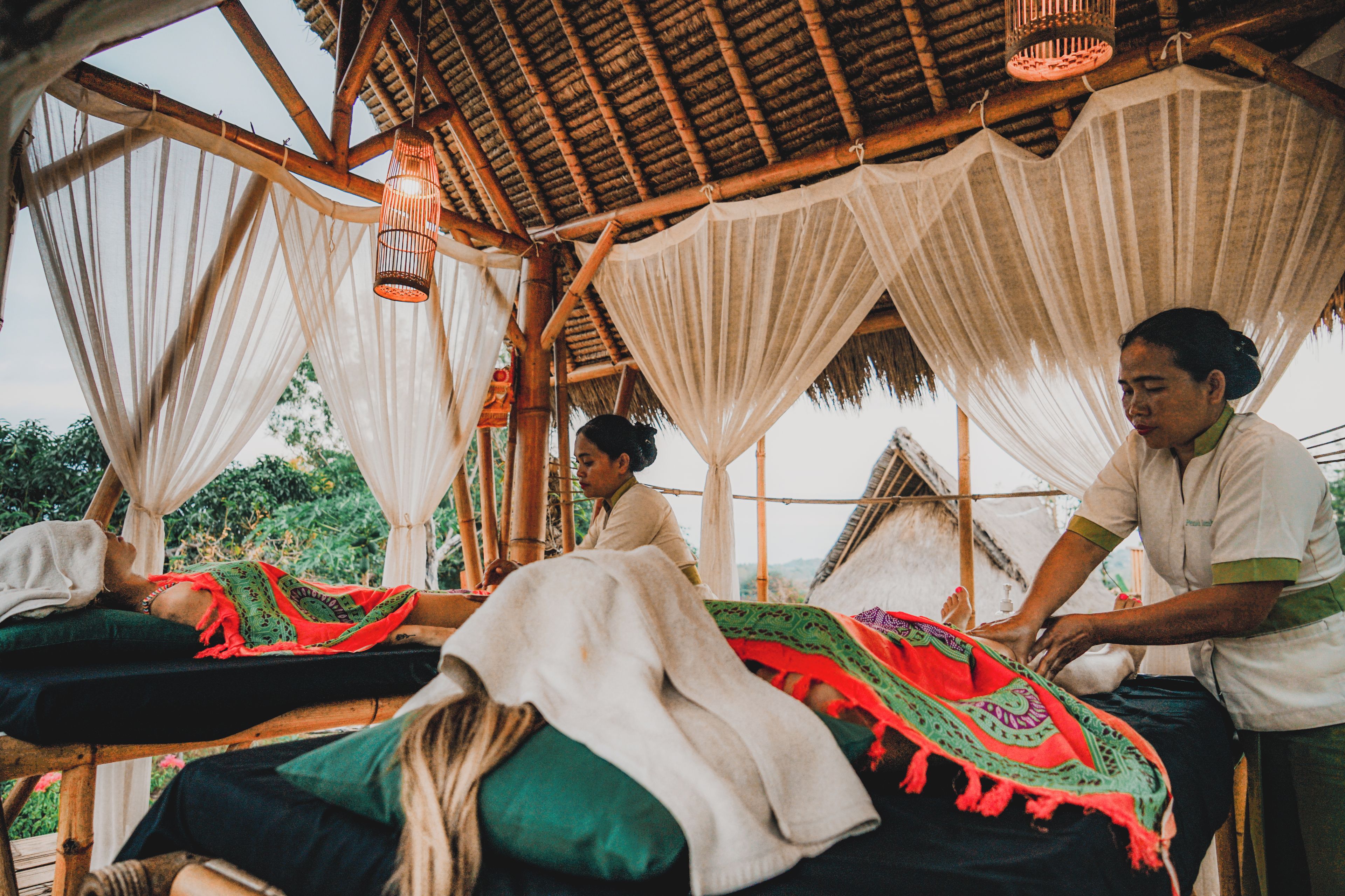 Un salón de masajes tradicional con vigas de madera, lámparas colgantes y telas drapeadas.