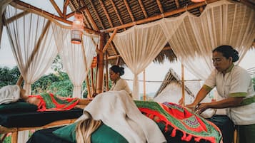 Un salón de masajes tradicional con vigas de madera, lámparas colgantes y telas drapeadas.