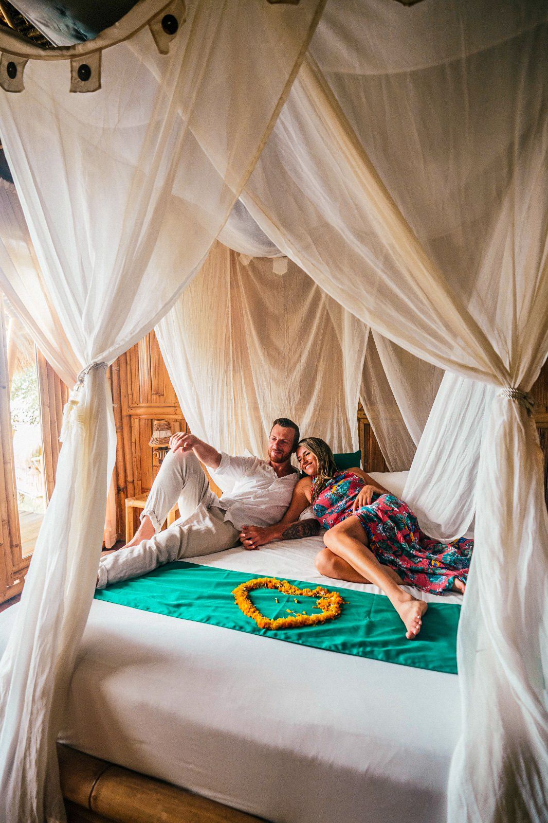 A bed with a canopy, a heart-shaped decoration, and a wooden floor.