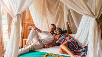 A bed with a canopy, a heart-shaped decoration, and a wooden floor.