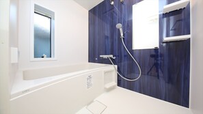 Une salle de bain moderne avec une baignoire, une douche et une fenêtre.