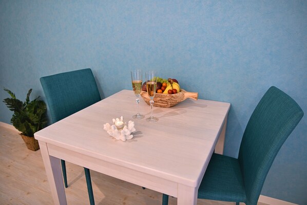 A table with a fruit bowl, two glasses of wine, and a candle.