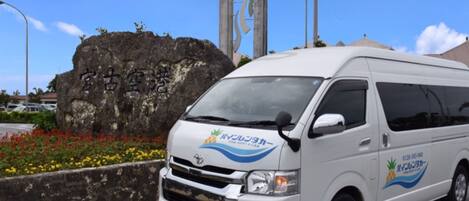 A white van with "Pineapple Rental Car" branding parked near a rock with Japanese characters.