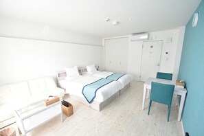 A modern bedroom with a bed, a desk, a chair, and a sofa. - Pine Hills Hotel Miyakojima (Miyakojima)