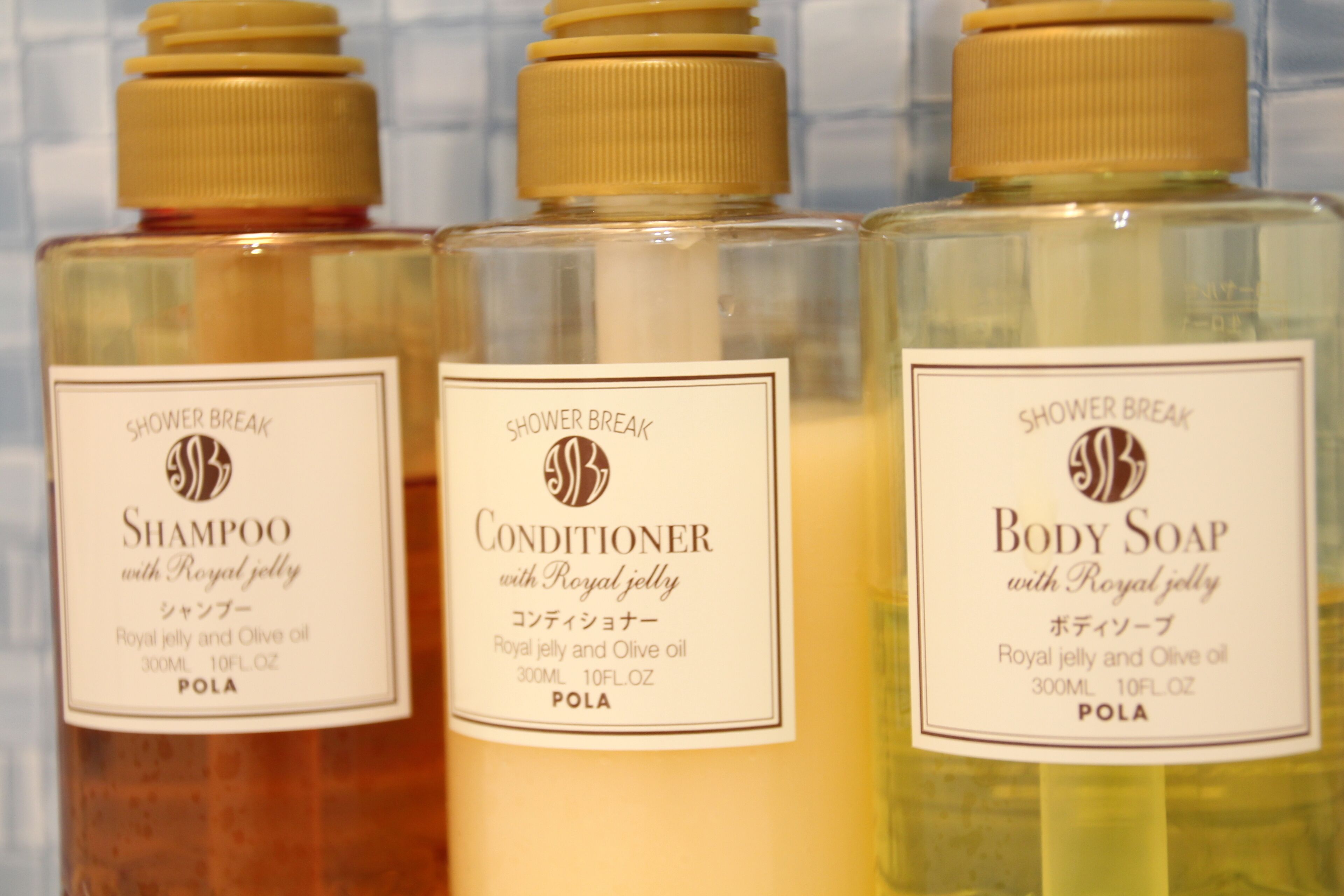 Three bottles of Shower Break products: Shampoo, Conditioner, and Body Soap, each with a label indicating they contain Royal jelly and Olive oil.