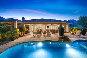 Ein modernes Haus mit Swimmingpool, Terrassenmöbeln und Blick auf die Berge.