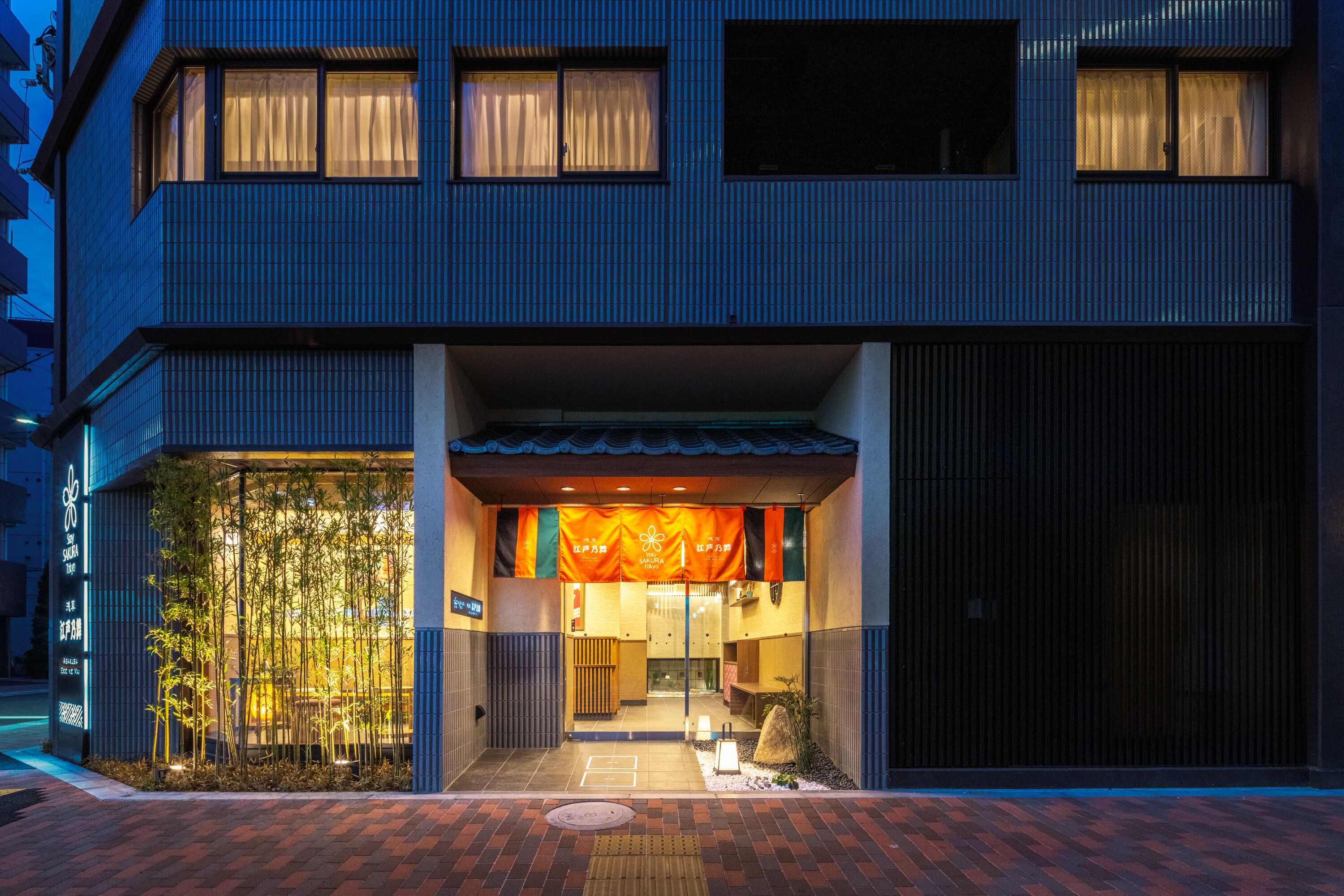 A modern building with a large entrance, a covered outdoor seating area, and a visible sign with Japanese characters.
