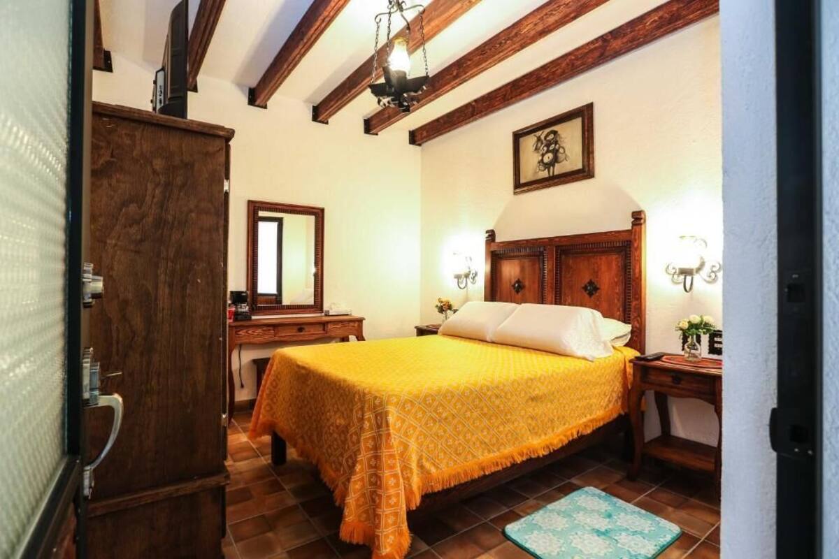Un dormitorio con una cama de madera, una mesita de noche, un tocador y un espejo.