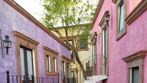 Un estrecho callejón con una escalera de piedra que sube a un balcón en un segundo piso.