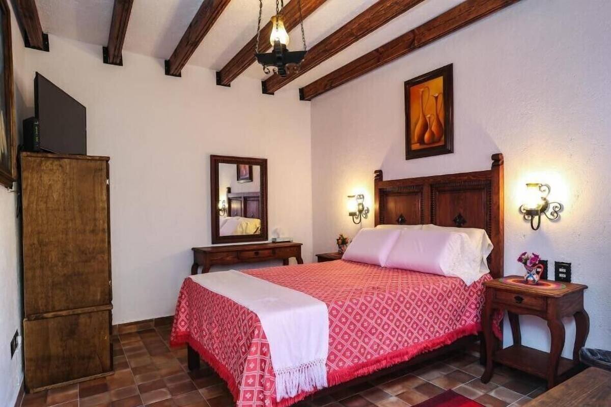 Un dormitorio con una cama de madera, una mesita de noche, un aparador y un espejo.