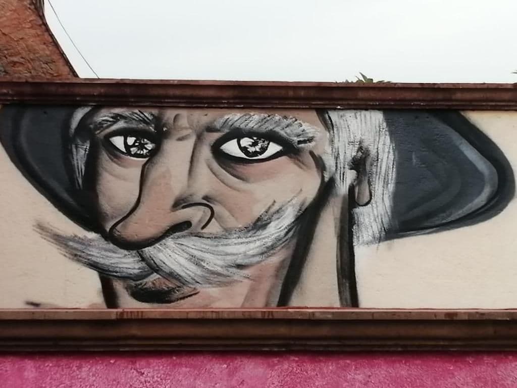 Een muur met een muurschildering van een persoon met een hoed.