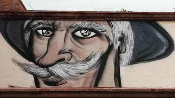 Eine Wand mit einem Wandgemälde, das eine Person mit Hut zeigt.