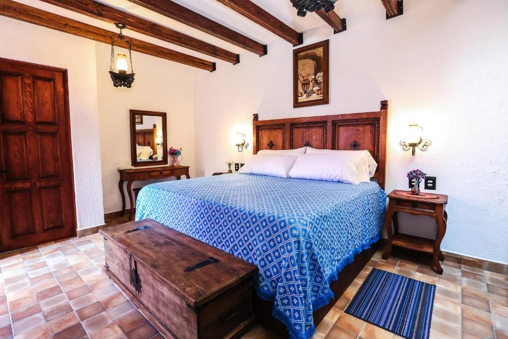 A bedroom with a wooden bed, a dresser, a nightstand, and a mirror.