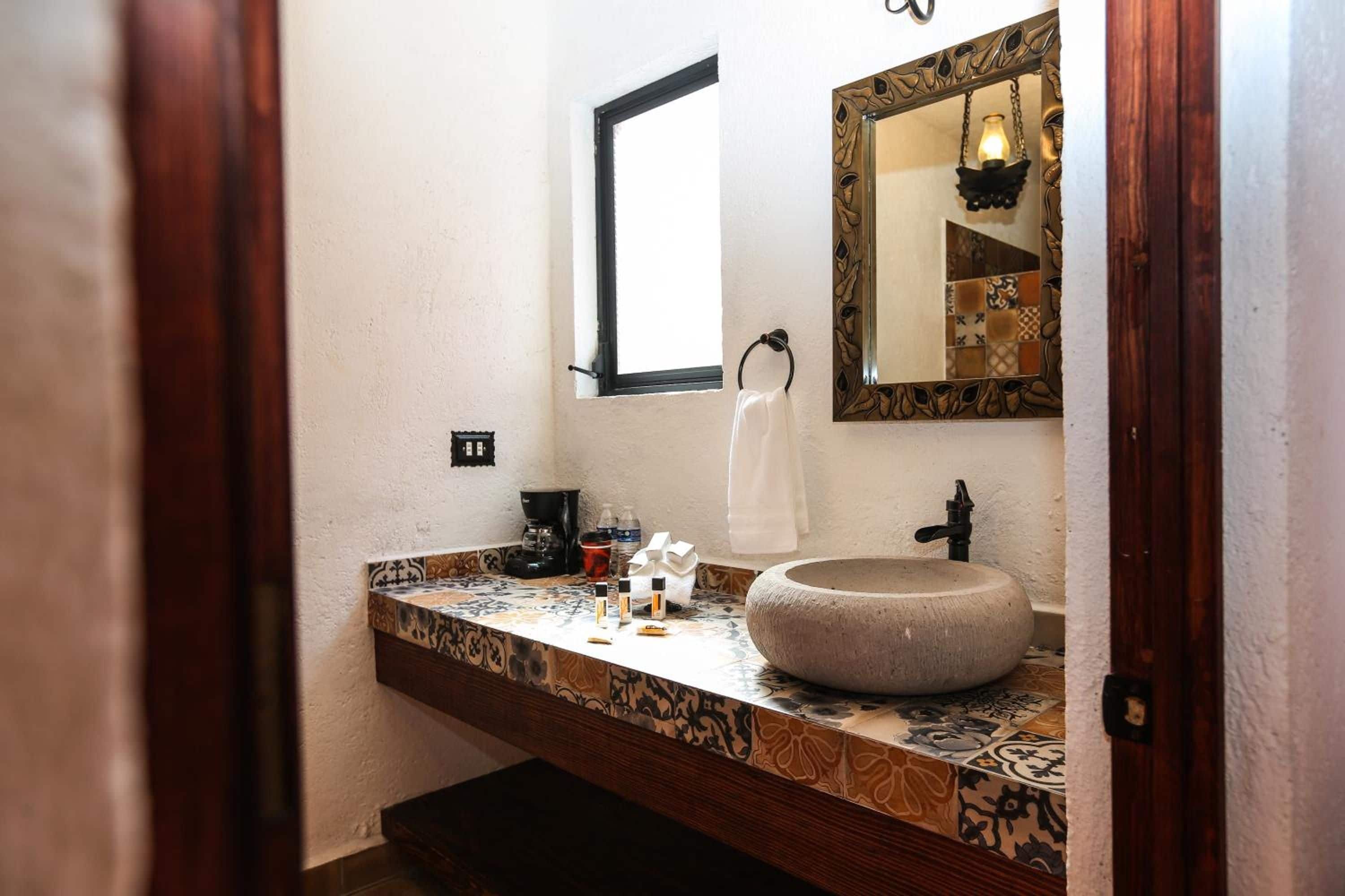 Une salle de bain avec un lavabo en pierre, une machine à café et une serviette suspendue à un porte-serviette.