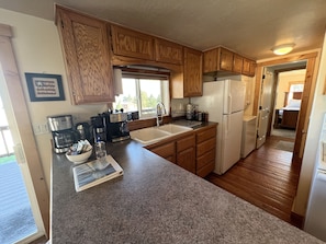 Kitchen features a sink, refrigerator, and coffee maker, with a doorway leading to a larger space.