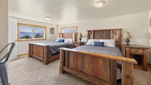 A bedroom with two wooden beds, a window with a view, and a ceiling light. - Outdoor adventures all around this comfy home with stunning views prime location (Hamilton)