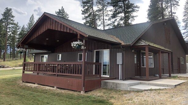 A rustic cabin with a wooden exterior, large windows, and a porch. - Outdoor adventures all around this comfy home with stunning views prime location (Hamilton)