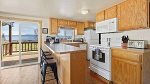 A kitchen with wooden cabinets, a central island, a large window, and a view of the outdoors. - Outdoor adventures all around this comfy home with stunning views prime location (Hamilton)