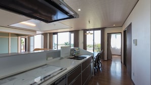 A modern kitchen with a large island, built-in appliances, and large windows offering views. - Comfort House in Miyakojima (Miyakojima)