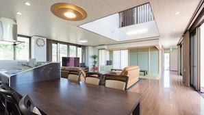 A spacious kitchen with a large island, wooden flooring, and a modern pendant light. - Comfort House in Miyakojima (Miyakojima)