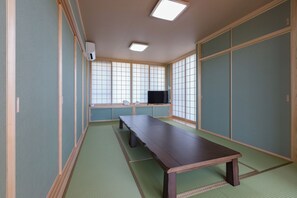 A traditional Japanese room with tatami flooring, a low table, sliding doors, and a television. - Comfort House in Miyakojima (Miyakojima)