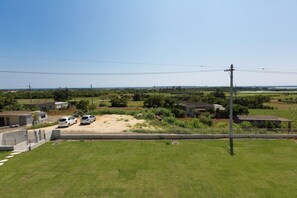 A grassy field with a few buildings and parked cars. - Comfort House in Miyakojima (Miyakojima)