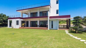 A modern two-story house with a covered patio and a well-maintained lawn. - Comfort House in Miyakojima (Miyakojima)