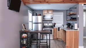 Una cocina moderna con armarios de madera, horno empotrado, microondas y cafetera.