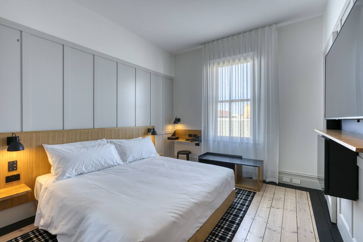 Une chambre d’hôtel moderne équipée d’un grand lit, d’un bureau, d’une chaise et d’un téléviseur.