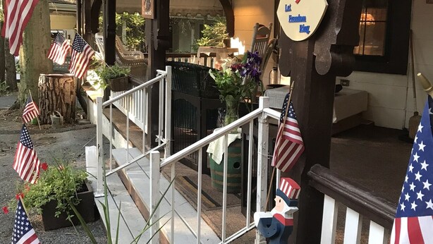 Ein Gebäude mit einer Veranda, verziert mit amerikanischen Flaggen, und einem Schild, auf dem 'Mr. Creason' steht.
