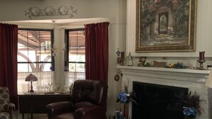 Ein Wohnzimmer mit Kamin, Ledersessel, Sofa und einem Gemälde an der Wand.
