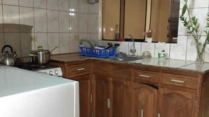 A kitchen with wooden cabinets, a stainless steel range hood, a blue dish rack, and a tiled backsplash. - Lhotse Hostel B&B Huaraz (Huaraz)