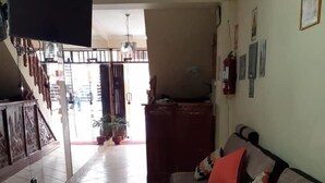 A living room with a sofa, a TV, and a staircase leading to another room. - Lhotse Hostel B&B Huaraz (Huaraz)