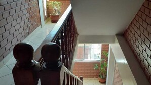 A staircase with wooden balusters and a tiled floor leading to an outdoor area with potted plants. - Lhotse Hostel B&B Huaraz (Huaraz)