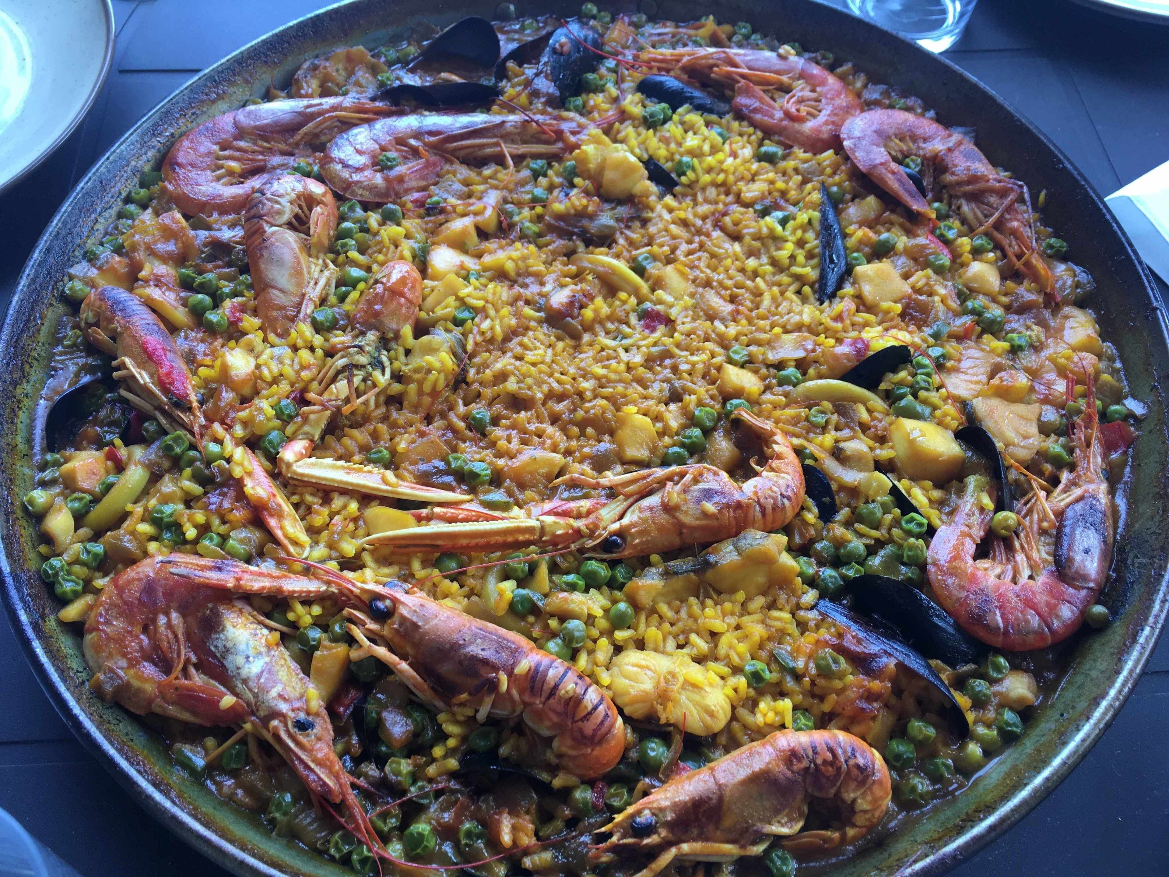 Een grote, ronde, ondiepe pan met paella, een gerecht met zeevruchten.