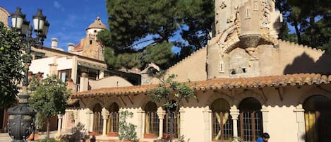 A courtyard with a chessboard, a tower, and a building with arched windows.